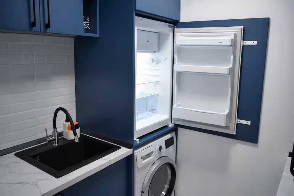 A small kitchen with a black dishwasher and a blue refrigerator — studio in Pitesti