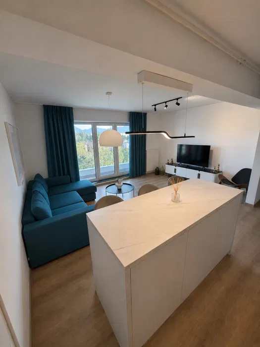 A living room with a sofa, a chair, a table, and a window — apartment in Brașov