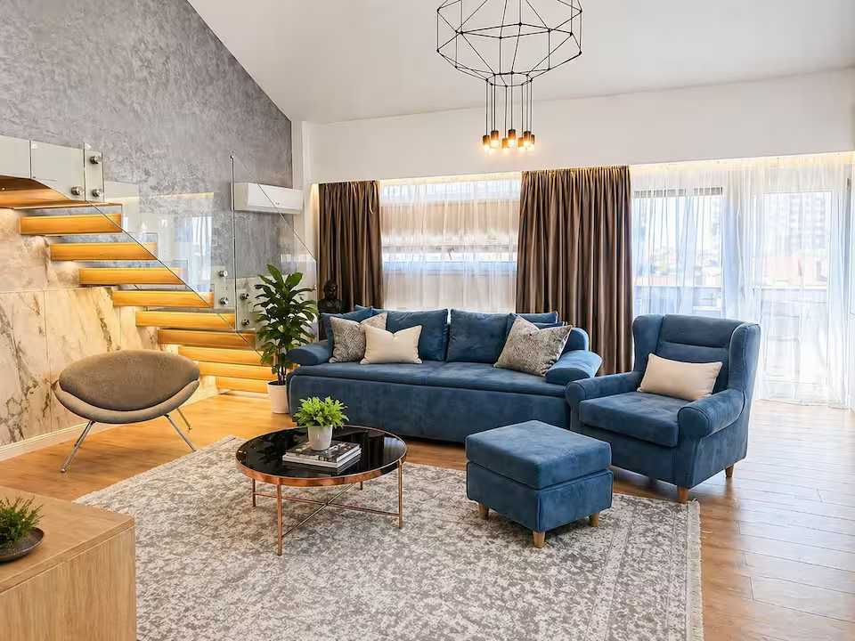 A living room with a blue sofa, a chair, a coffee table and a plant with pot — apartment in Oradea