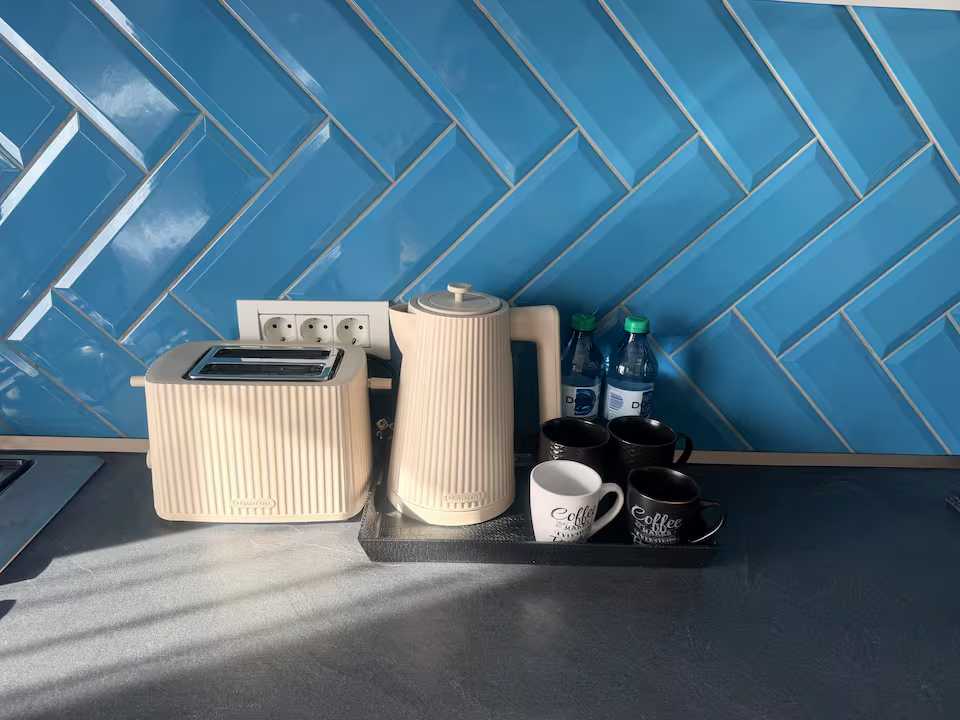 A kitchen with a coffee machine, a tea boiler and water bottles — apartment in Oradea