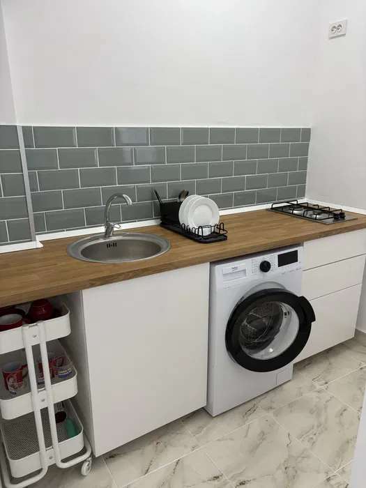 A small kitchen with a cup, a dryer and a window