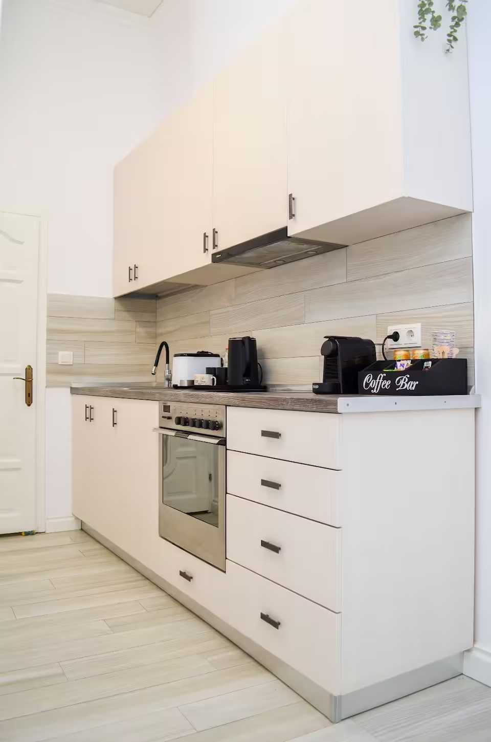 A kitchen with a white oven, white cabinets and a coffee machine — studio in Oradea