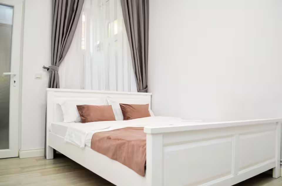 A room with a white bed and a window — studio in Oradea