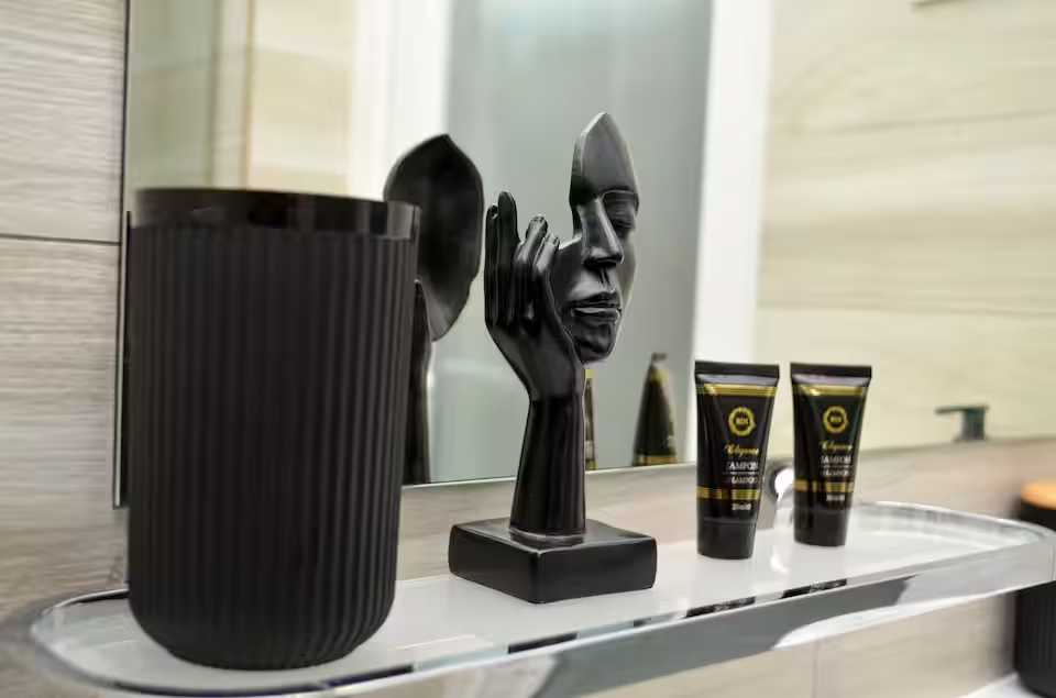 A black and white bathroom with mirror and a black vase — studio in Oradea