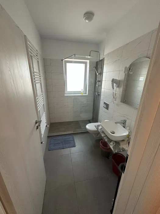 A small bathroom with a white toilet and a window — studio in Brașov