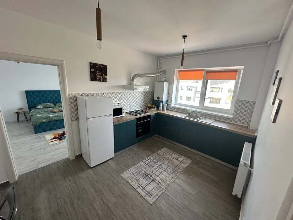 A small kitchen with a fridge, stove, and sofa — studio in Brașov