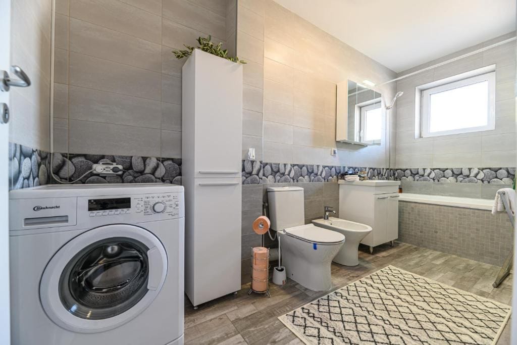 A bathroom with toilet, dishwasher and washing machine — apartment in Brașov
