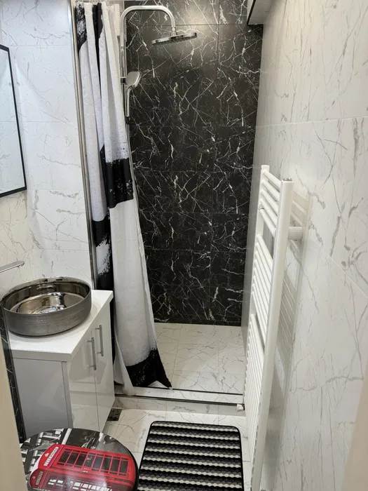 A bathroom with a white shower curtain and a shelf of white towels