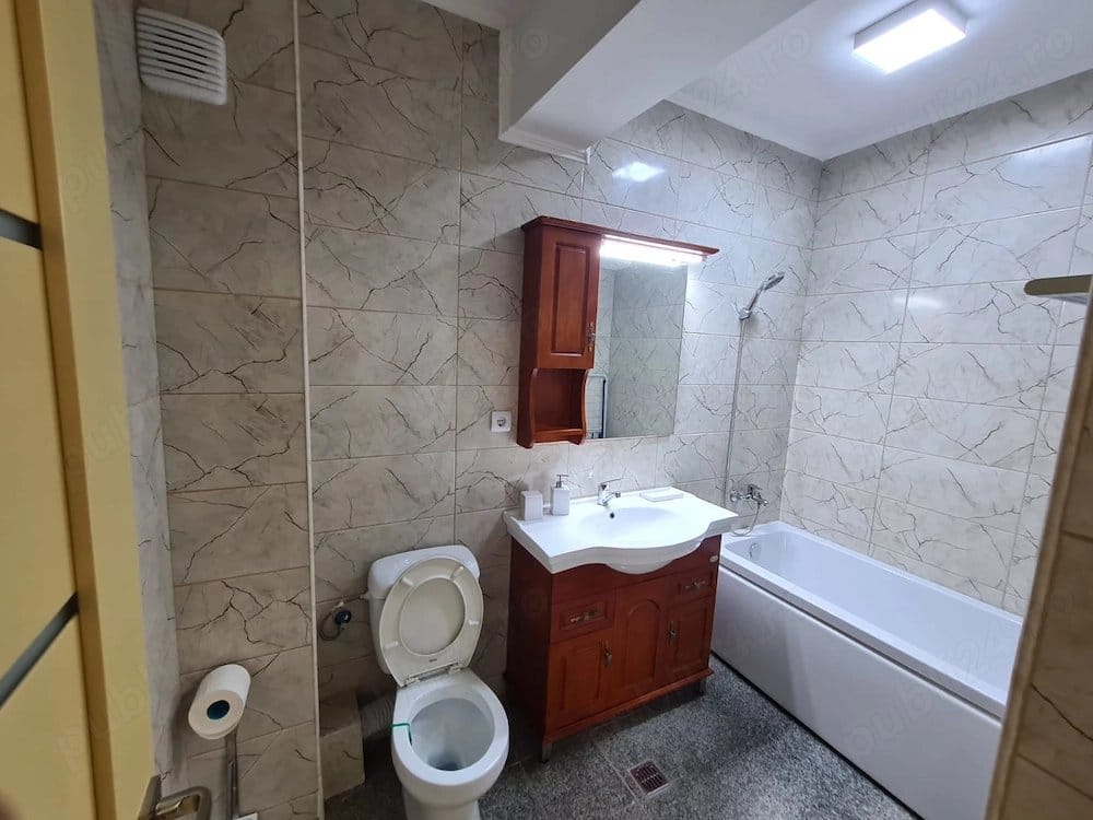 A bathroom with a toilet, sink, and mirror