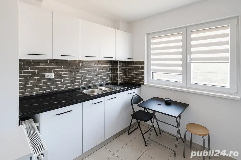 A small, clean, white kitchen with a black top and a window