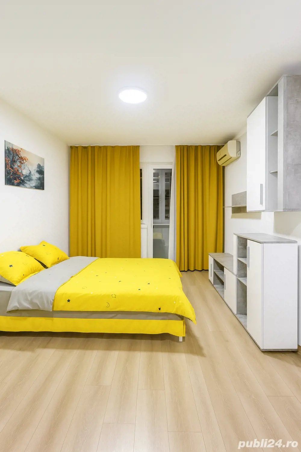 A room with a bed, a window and a yellow curtain