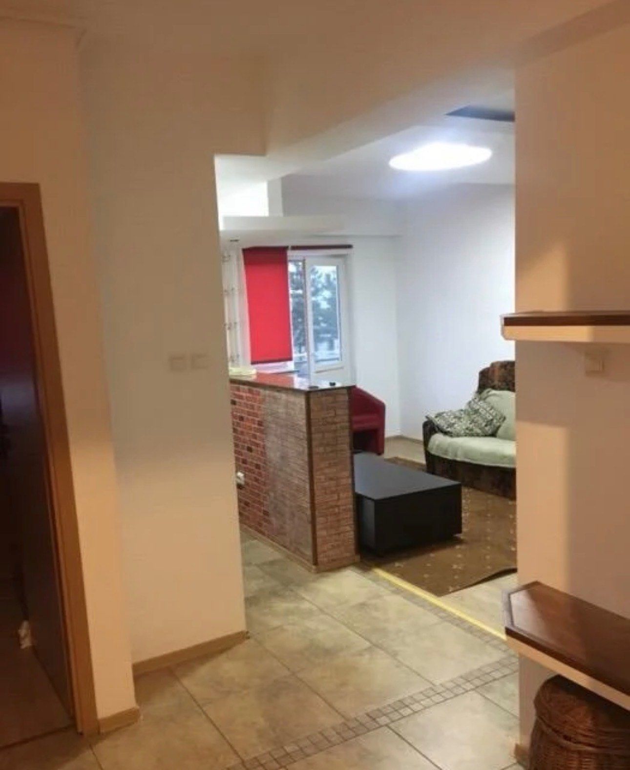A living room with a sofa, a chair and a brick wall