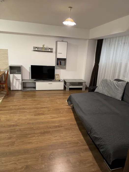 A living room with sofa, TV and window