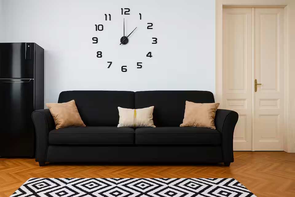 A black sofa with pillows and a watch on the wall — apartment in Oradea