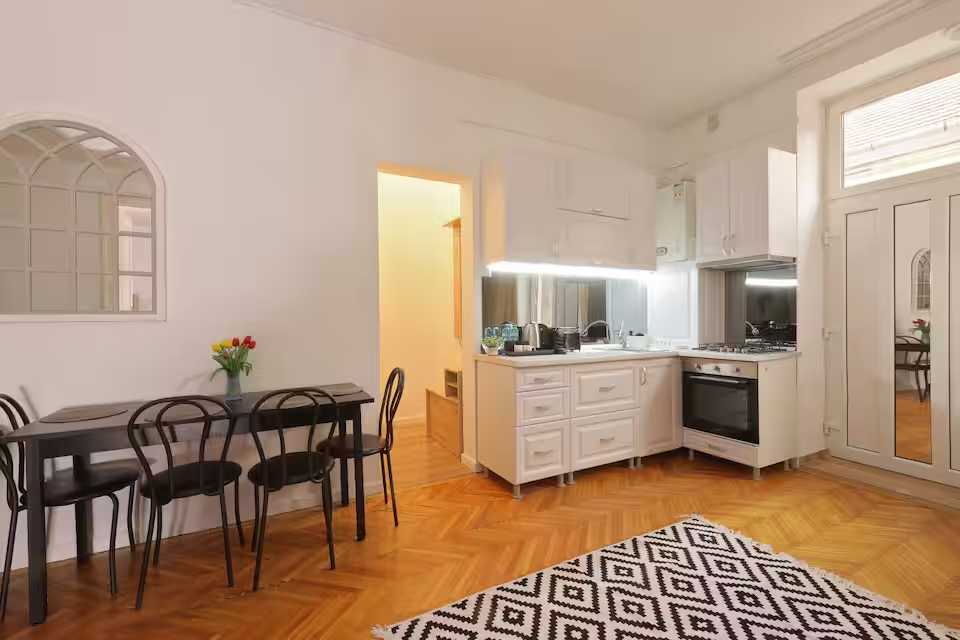 A kitchen with white cabinets and a table — apartment in Oradea