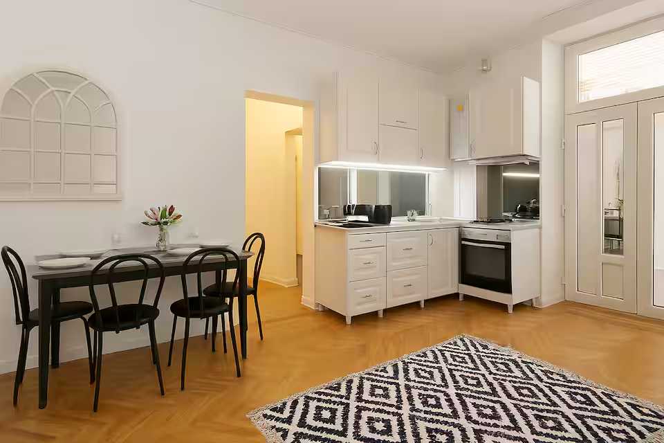 A kitchen with white cabinets and a table — apartment in Oradea