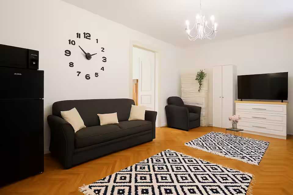 A living room with sofa, chair and clock — apartment in Oradea