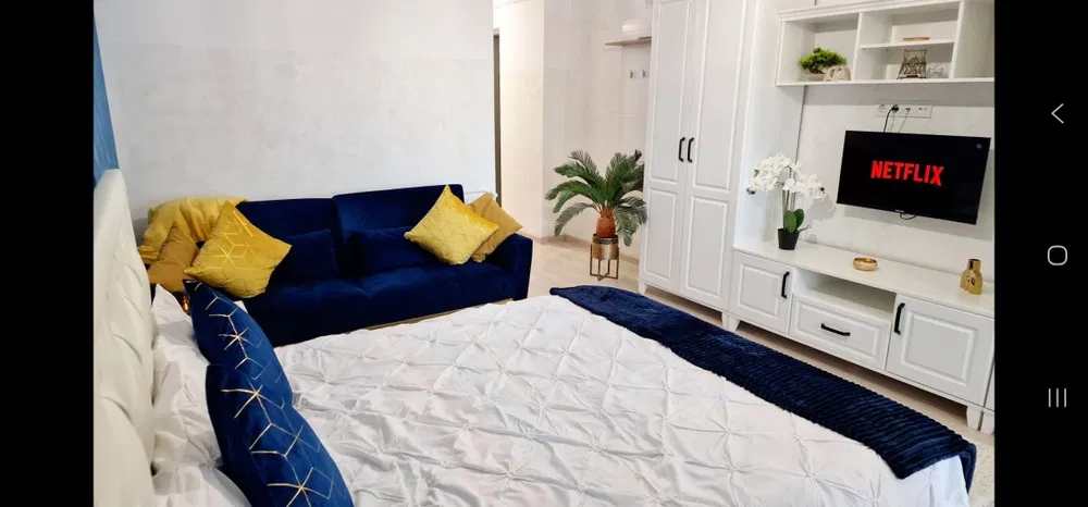 A blue sofa with yellow pillows and a blue bed with a white comforter